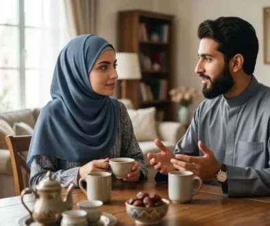 Alt Text: A young Muslim couple sitting together at a wooden table in a warm, cozy home, engaging in a supportive and deep conversation over tea and dates, symbolizing emotional connection and healthy communication in an Islamic marriage.