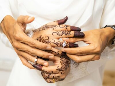 Hands with henna exchanging wedding rings, symbolising questions to ask before marriage in Islam