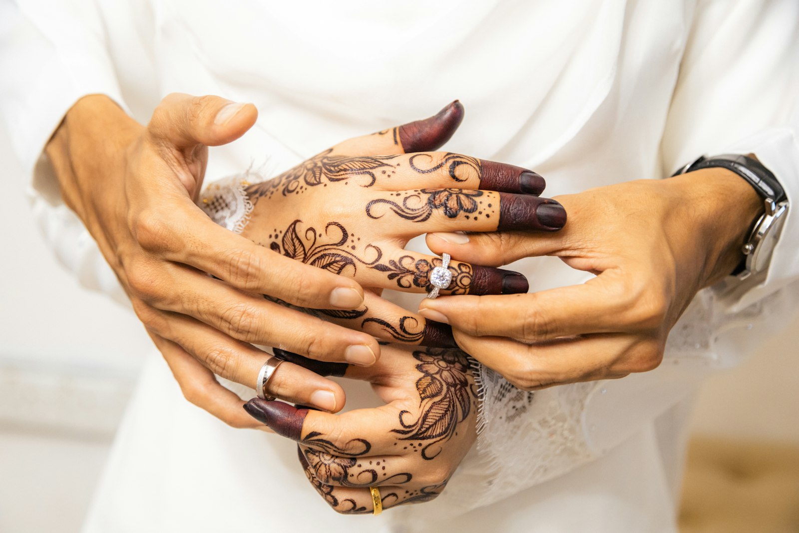 Hands with henna exchanging wedding rings, symbolising questions to ask before marriage in Islam